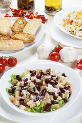 Delicious bean salad with various vegetables and toast bread arranged on the white table with fresh garlic, peppers and tomatoes.
