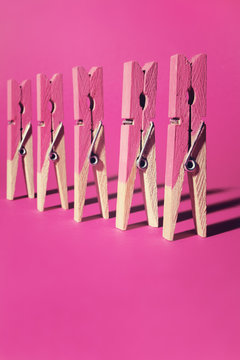 Row of pink painted clothes pegs on pink background