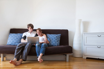 young family using laptop at home, couple on the couch with computer