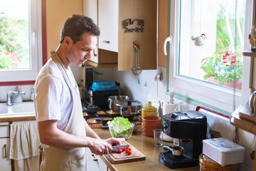 cooking healthy food, young male cutting tomatoes in the kitchen