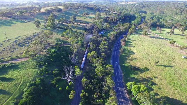 Aerial footage of classic historical railway vintage steam train locomotive SteamRanger (Steam Ranger) climbing hill after travel in Adelaide Hills and countryside for South Australian Tourism
