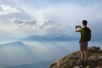 Fototapeta na wymiar hiker taking photo of beautiful mountain landscape with mobile phone