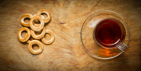 Fototapeta premium Cup of tea, bagels dry on the old rustic table wood background.