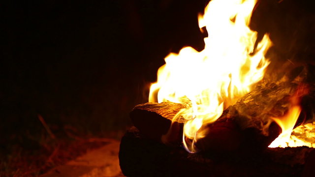 Campfire Right Close Up. a close up shot of a campfire at night. justified right. stack of wood.
