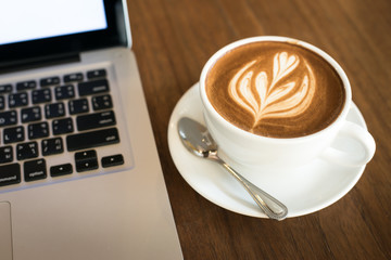 Hot art Latte Coffee in a cup and laptop on wooden table in Coff