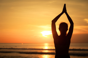 woman open arms under the sunset at sea