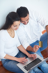 relaxed young couple working on laptop computer at home