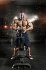 Fototapeta na wymiar Athlete muscular bodybuilder man demonstrates his muscles in gym