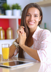 Woman using a tablet computer while drinking tea in her kitchen