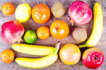 Fresh fruits on wooden background. Summer background. Raw and vegetarian eating background. Lemon, apple,  grapefruit, pomegranate, lime, persimmon, tangerine, orange, banana. Top view
