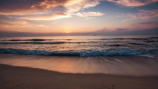 Dramatic sunrise over beautiful beach, sea waves splashing on the coastline