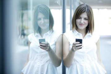 Fototapeta na wymiar bella ragazza con capelli biondi sorride mentre legge un messaggio sul telefono
