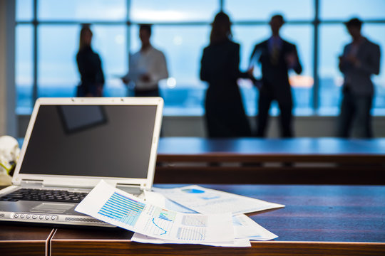 Silhouette of office workers businessmen in refocuse, at the forefront of the laptop and documents