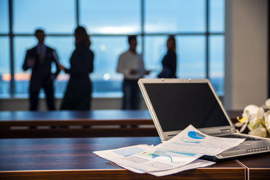 Silhouette of office workers businessmen in refocuse, at the forefront of the laptop and documents