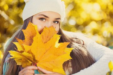 Excited happy woman smiling joyful and blissful holding autumn leaves outside in colorful fall...
