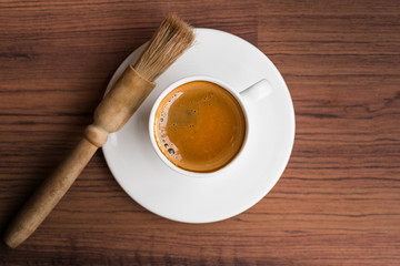 cup of fresh espresso with cleaning blush of coffee machine on table, view from above