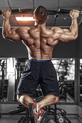 Fototapeta na wymiar Muscle athlete man in gym making Pull-up. Bodybuilder training in gym