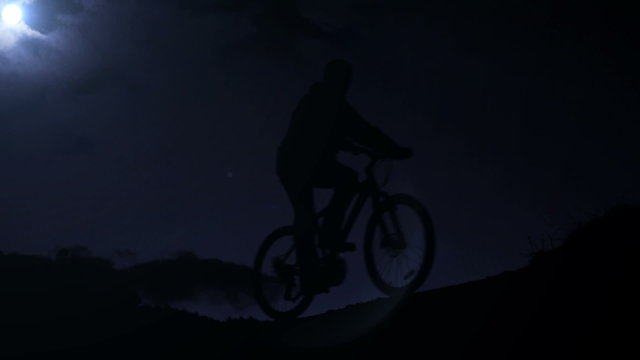 A footage of a biker's silhouette passing the mountain ridge