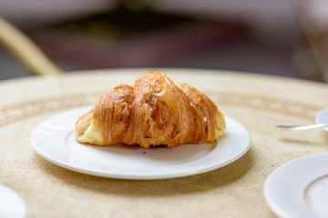 French croissant on white plate on a restaurant table