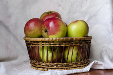 Яблоки в плетеной корзинке на светлом фоне