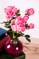 Pink roses in a vase on wooden background