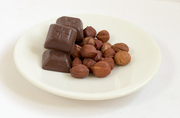 Chocolate and nuts in a white plate composition