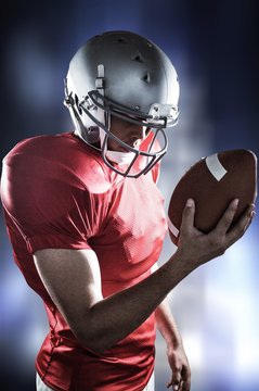 Composite image of american football player looking at ball 