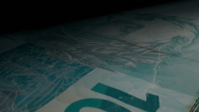 An extreme closeup of brazilian real banknotes flipping through in a counting machine