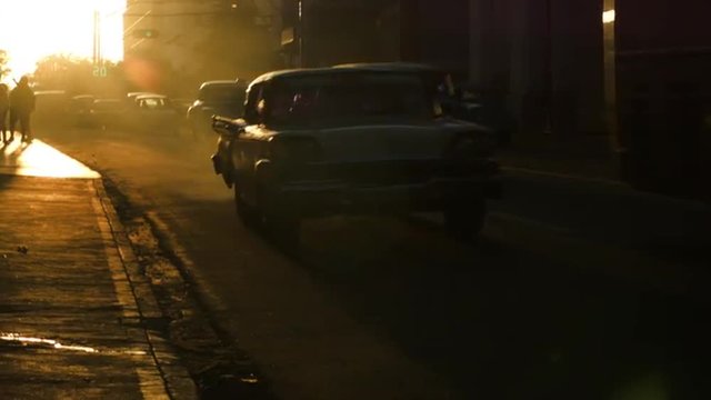 Pedestrians and cars in the sunset glow silhouettes in Havana