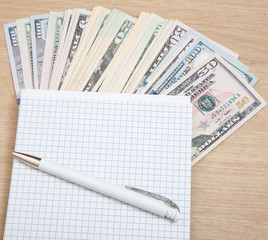 Various dollar notes next to notepad