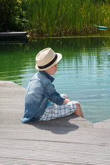 little boy sitting at the pool and looking into the water