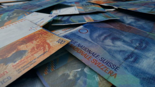 An extreme close up pan of a pile of randomly scattered swiss franc banknotes