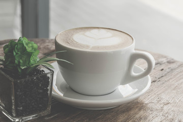 Close up a cup of coffee latte art on old wooden background - Vintage filter effect