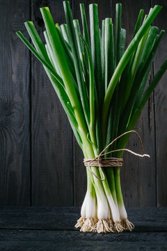 Scallions on a black wooden background close-up