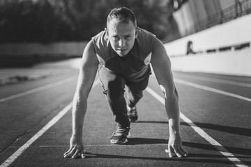 Athletic man standing in posture ready to run on a treadmill