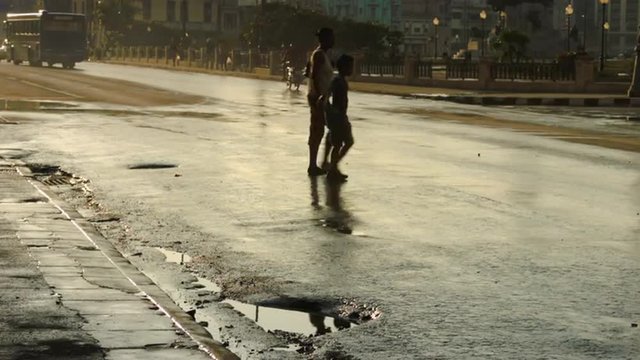 Pedestrians crossing on wet street in Havana