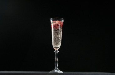 Glass of champagne with strawberries isolated on black background
