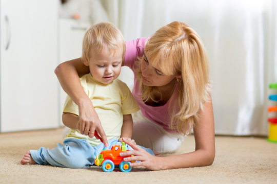 mother and son playing with toy cars indoors