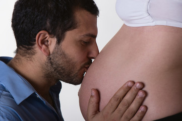 Love. Man kissing pregnant belly of his wife on white