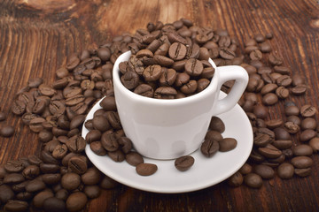 Roasted brown coffee beans & mug on wooden table