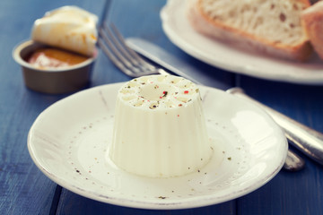 fresh cheese on white plate with fish pate and bread on blue wooden background