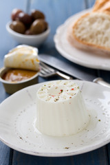 fresh cheese on white plate with fish pate and bread on blue wooden background