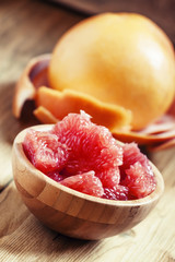 Juicy flesh pink grapefruit in the wooden bowl, selective focus