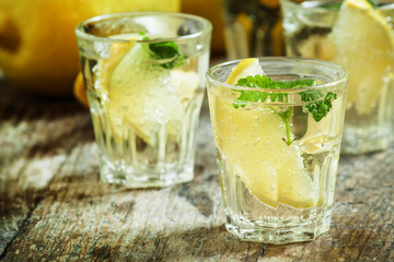 Carbonated lemonade with lemon slices and mint on an old wooden