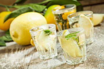 Carbonated lemonade with lemon slices and mint on an old wooden