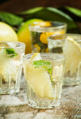 Carbonated lemonade with lemon slices and mint on an old wooden