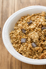 cereals with chocolate on white bowl on brown wooden background