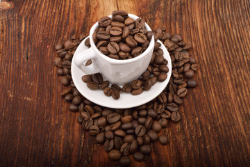 Roasted brown coffee beans & mug on wooden table