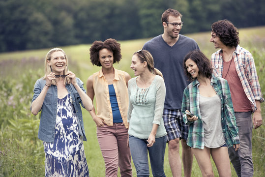 A group of people, a man and five women, walking through the countryside. 