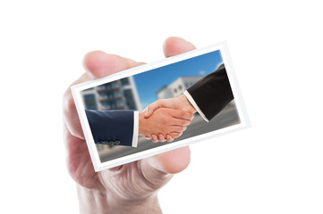 Business people handshake on card hold by human hand